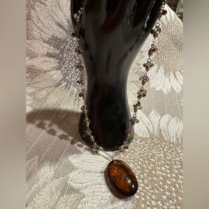 Beautiful amber stone hangs from chain with delicate clusters of small beads.